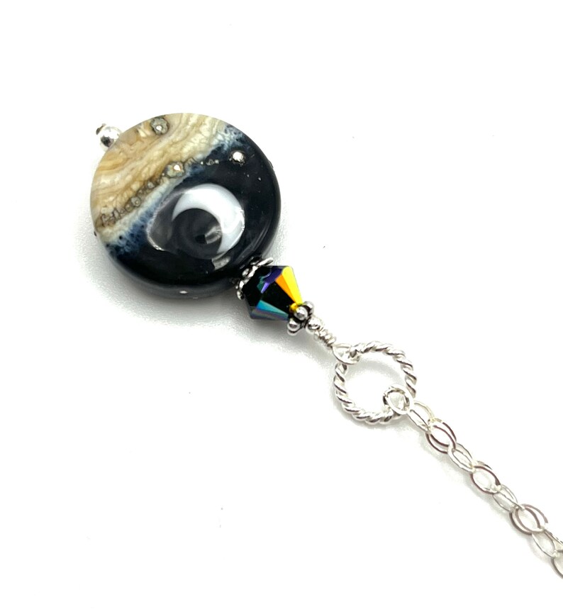 May include: A silver chain necklace with a black and white glass bead and a crystal accent.