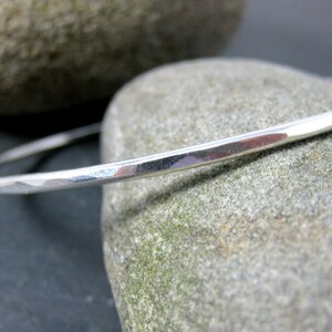 May include: A silver bangle bracelet with a hammered finish. The bracelet is simple and elegant, and would make a great gift.