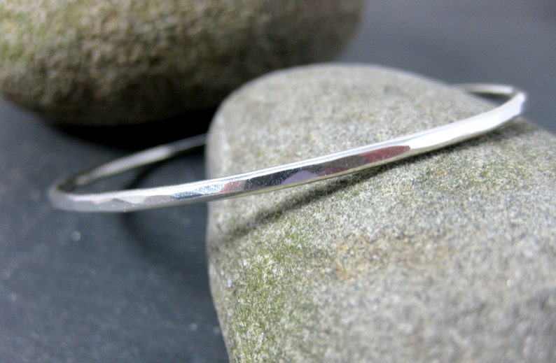 May include: A silver bangle bracelet with a hammered finish. The bracelet is simple and elegant, and would make a great gift.