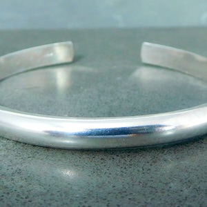 May include: A simple silver bangle bracelet with a smooth, polished finish.