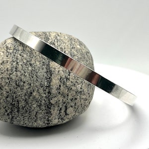 May include: A silver bangle bracelet with a smooth, polished finish. The bracelet is simple and elegant, and would make a great gift.