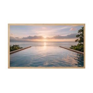 May include: A framed photograph of an infinity pool overlooking the ocean at sunset. The water in the pool reflects the sky's colors, with a wooden border on each side. Lush green plants frame the edges.
