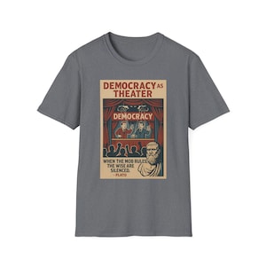 May include: Grey t-shirt with a graphic that reads "DEMOCRACY AS THEATER." The design shows a stage with actors, the word "DEMOCRACY," and a quote by Plato: "WHEN THE MOB RULES, THE WISE ARE SILENCED."