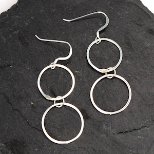 May include: Silver dangle earrings with three connected circles. The circles are hammered and have a textured finish.
