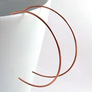 May include: A pair of large, simple copper hoop earrings. The hoops are thin and have a smooth, polished finish.