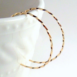 May include: A pair of gold-toned hoop earrings with a twisted design.