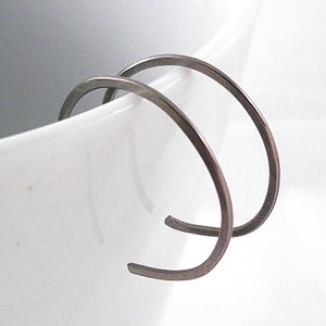 May include: A pair of silver hoop earrings. The earrings are simple and elegant, with a smooth, polished finish.