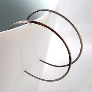 May include: A pair of silver hoop earrings. The hoops are thin and delicate, and they are made of a smooth metal.