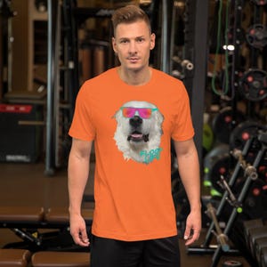 May include: Orange short-sleeved t-shirt with a white dog wearing pink and blue sunglasses. The dog's head is centered on the shirt and the text "Flock Life" is below the dog's head.
