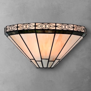 May include: A semi-circular wall sconce featuring a stained glass shade with a geometric black metal frame. The shade consists of translucent cream and pale peach glass panels arranged in a fan pattern, topped with a repeating diamond border.