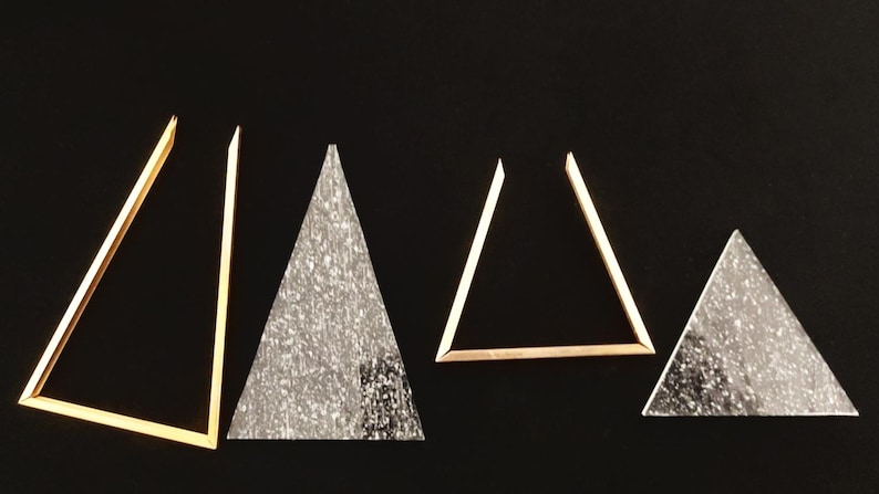 May include: Five gold-colored triangles of varying sizes, with two of the triangles filled with a sparkly, silver-colored material.
