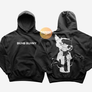 May include: Black hoodie with the text "DUMB BUNNY" on the front. The back features a white graphic of a fox in a shirt and tie. The hoodie has a hood and a front pocket.