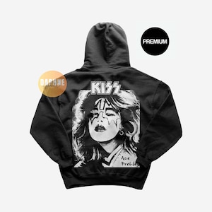 Può includere: Felpa con cappuccio nera con una grafica in bianco e nero di Ace Frehley della band KISS. L'immagine include il logo della band e il nome "Ace Frehley". La felpa ha un'etichetta "Premium".
