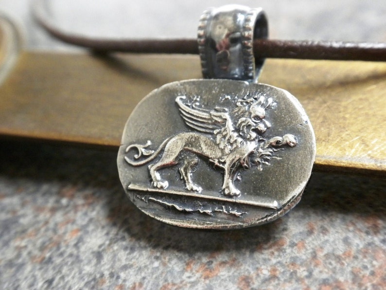 Silver winged lion of Venice pendant.  The winged lion has sharp details and the silver pendant has been oxidized to bring out the details.  The bail is a loop bail that has been soldered.