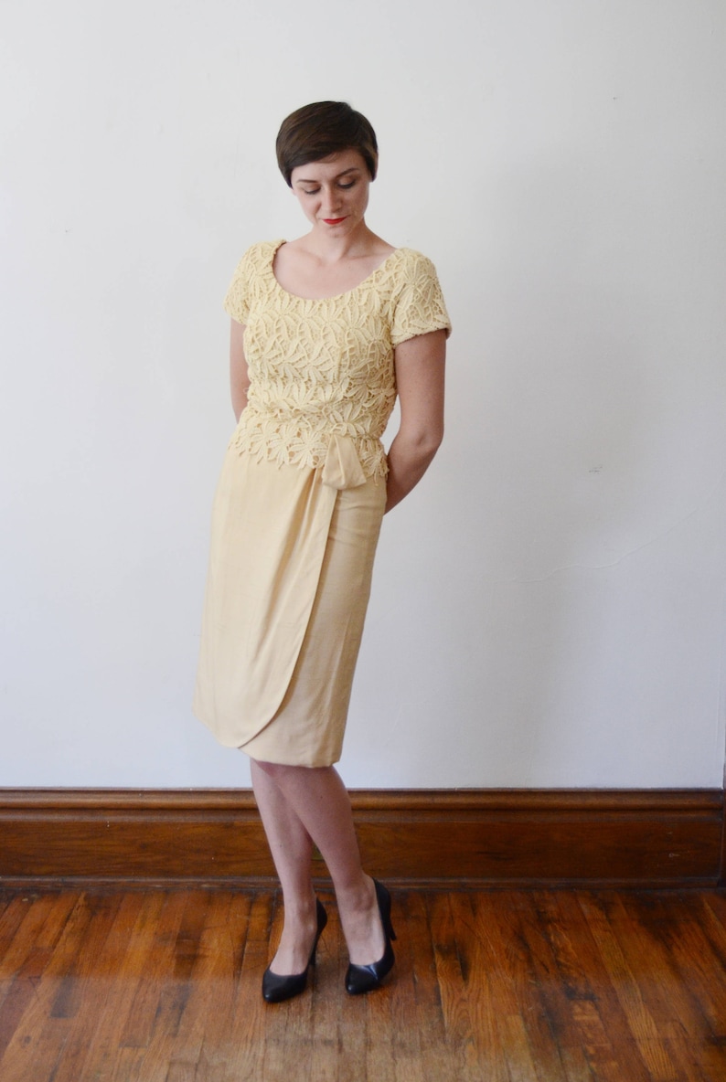 Puede incluir: Una mujer con un top de encaje amarillo y una falda amarilla a juego. Est&aacute; de pie sobre un suelo de madera y tiene el pelo corto y casta&ntilde;o.