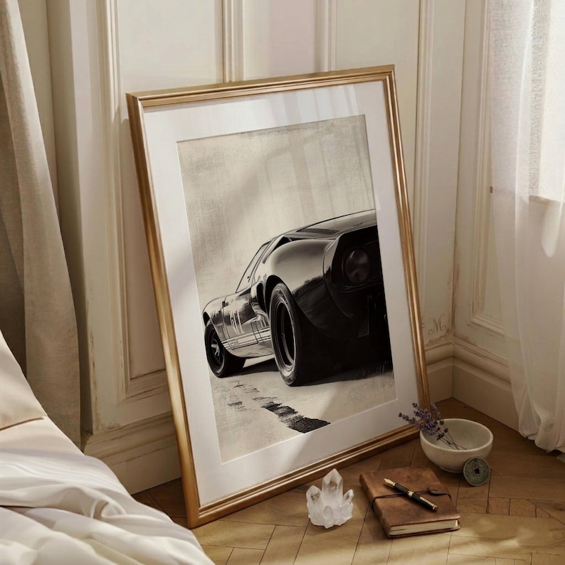 Peut inclure: Impression en noir et blanc d'une voiture de sport classique, encadr&eacute;e dans un cadre dor&eacute;. L'image montre l'arri&egrave;re et le c&ocirc;t&eacute; de la voiture sur une route. Le cadre est pos&eacute; contre un mur.