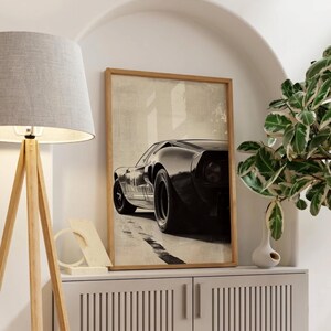 Peut inclure: Impression encadr&eacute;e d'une voiture de sport noire vintage, vue d'en bas, avec une bande blanche sur le c&ocirc;t&eacute;. L'&oelig;uvre est plac&eacute;e sur un fond neutre, cr&eacute;ant une &oelig;uvre d'art automobile classique.