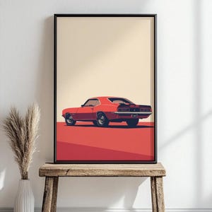 May include: A framed wall art print featuring a stylized illustration of a red muscle car viewed from the rear three-quarter angle. The car has black racing stripes, dark wheels, and is set against a solid cream background with a red ground plane.