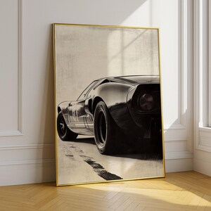 Peut inclure: Impression encadr&eacute;e en noir et blanc d'une voiture de sport classique. L'&oelig;uvre d'art pr&eacute;sente une vue de l'arri&egrave;re de la voiture, mettant en valeur son design &eacute;l&eacute;gant et ses grands pneus. L'impression est encadr&eacute;e d'or.