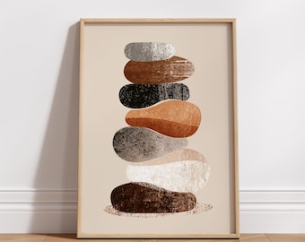 May include: A framed wall art print featuring a vertical stack of seven smooth, rounded stones in shades of gray, brown, black, tan, and white. The stones have a textured, speckled appearance and are centered on a light beige background.