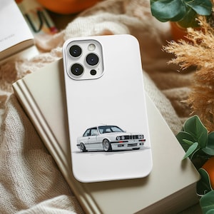 Puede incluir: Funda de teléfono blanca con una ilustración detallada de un coche blanco clásico. La funda está sobre un libro cerrado, con un fondo neutro. La funda del teléfono tiene un módulo de cámara con cuatro lentes.