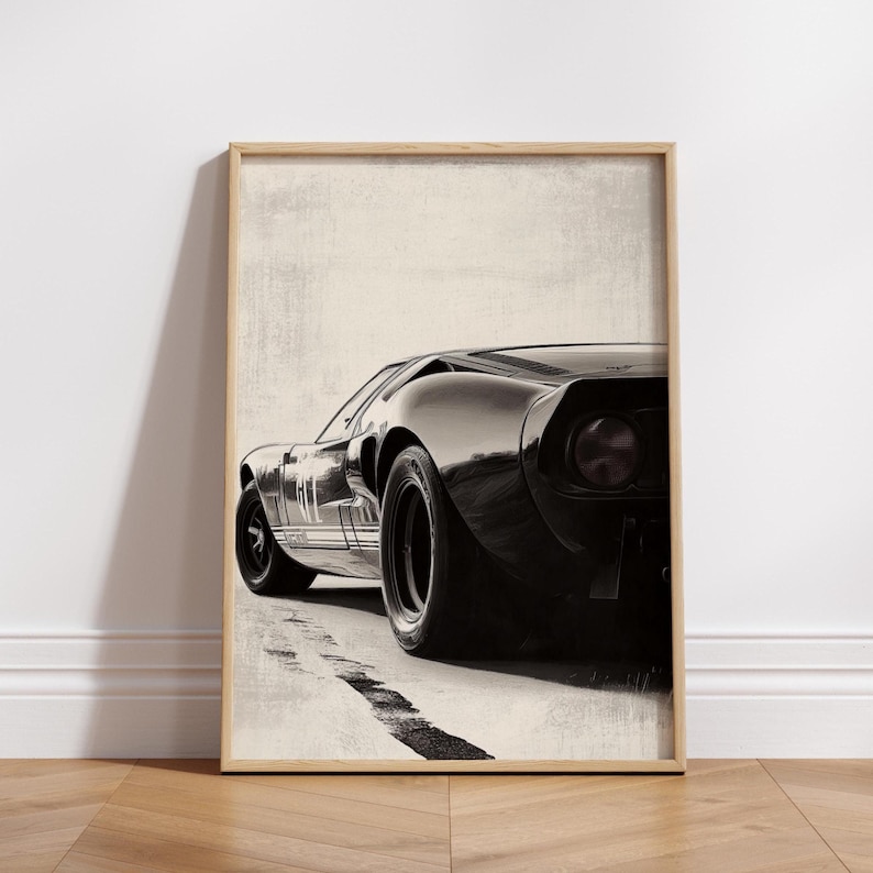 Peut inclure: Impression encadr&eacute;e d'une voiture de sport noire vintage, vue de trois quarts arri&egrave;re. La voiture a un profil bas et &eacute;l&eacute;gant avec de gros pneus et un feu arri&egrave;re distinctif. L'&oelig;uvre est sur fond neutre, avec une trace de pneu noire.