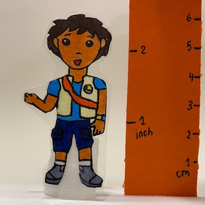 May include: A hand-drawn illustration of a cartoon character wearing a blue shirt, a beige vest, and blue shorts. The character is standing next to a ruler that measures 6 inches.