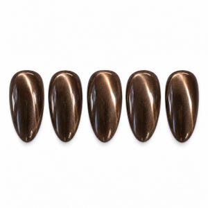 May include: Five almond-shaped nail tips arranged in a horizontal row. Each tip features a deep, metallic brown cat-eye polish finish with a distinct, shimmering diagonal light streak running through the center of the dark brown surface.
