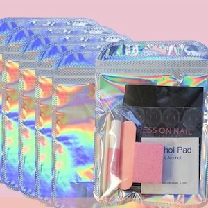 May include: Five holographic, iridescent resealable pouches containing nail application kits. Each kit includes a wooden cuticle stick, a small tube of nail glue, a pink nail file, a pink buffer block, and a white alcohol pad labeled Press on Nail.