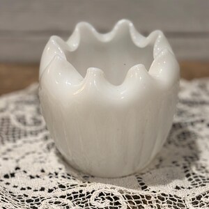 May include: White ceramic bud vase with a ruffled top and a textured, ribbed design.