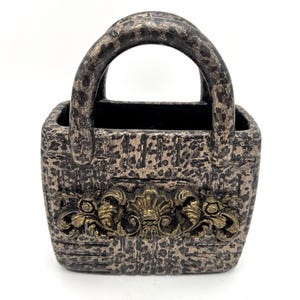 May include: A set of three ceramic mugs with a speckled, matte finish. The mugs are in shades of cream, light gray, and dark gray. Each mug has a simple, minimalist design and a rounded handle.