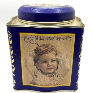 May include: Vintage blue tin with a gold rim and lid. The tin features a label with a portrait of a baby and the text "Clark's MILE-END'S SPOOL COTTON". Gold floral designs adorn the sides of the tin.