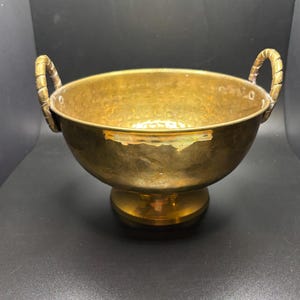 May include: A hammered brass bowl with two twisted wire handles and a round pedestal base.