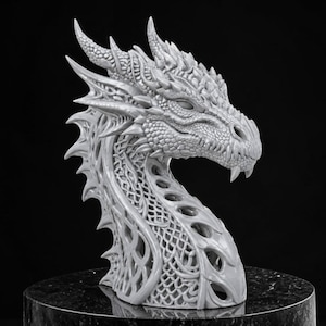 May include: A detailed, gray dragon head sculpture with intricate scales, horns, and a textured surface. The dragon's neck features an open, lattice-like design. The sculpture is displayed on a dark, round pedestal, showcasing fantasy art.
