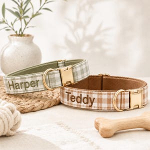Puede incluir: Dos collares de tela para mascotas con un patrón de cuadros vichy en verde salvia y marrón. Cada collar incluye una hebilla de metal dorado y una anilla en D. El collar verde salvia está bordado con el nombre Harper y el marrón con Teddy.