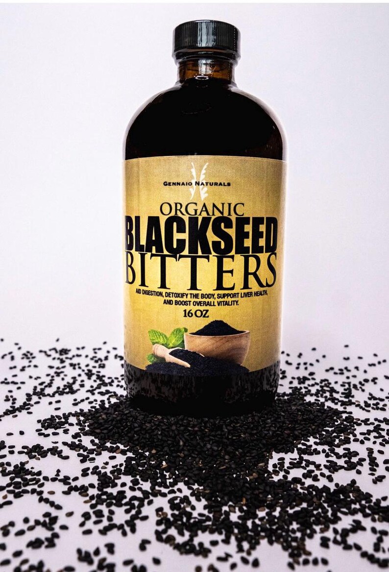 Puede incluir: Una botella de vidrio de amargos de semillas negras org&aacute;nicos con una etiqueta dorada que dice "GENNAIO NATURALS ORGANIC BLACKSEED BITTERS AID DIGESTION, DETOXIFY THE BODY, SUPPORT LIVER HEALTH AND BOOST OVERALL VITALITY. 16 OZ". Semillas de s&eacute;samo negras est&aacute;n esparcidas alrededor de la botella.