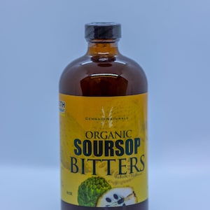 Puede incluir: Una botella de vidrio de amargos de guan&aacute;bana org&aacute;nica, con una etiqueta amarilla que dice "Organic Soursop Bitters" y "Gennaio Naturals". La botella est&aacute; llena de un l&iacute;quido marr&oacute;n oscuro.