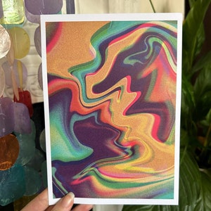 May include: An art print with an abstract, swirling design. The artwork uses a mix of colours, including gold, purple, green, and red, to create a dynamic visual effect. The print is set against a white border, enhancing the colours.