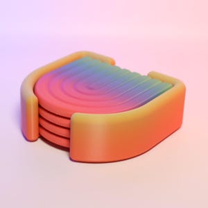 May include: A set of four colourful coasters with a rainbow gradient design. The coasters are stacked and have a rounded shape.