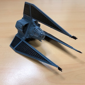 May include: A gray TIE Interceptor starfighter model with black details and a clear cockpit. The model has two sets of wings and is posed in flight.