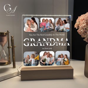 May include: A lighted acrylic photo display with a wooden base. The display features six family photos and the text "You Are The Best Grandma In This World" and "GRANDMA we love you". The names Emma, Amelia, and Emily are also included.