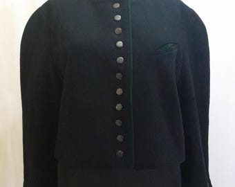 May include: A black jacket with a round collar and silver buttons down the front. The jacket has a green trim along the collar and pocket. The sleeves have buttons at the cuffs. The jacket is displayed on a black mannequin.
