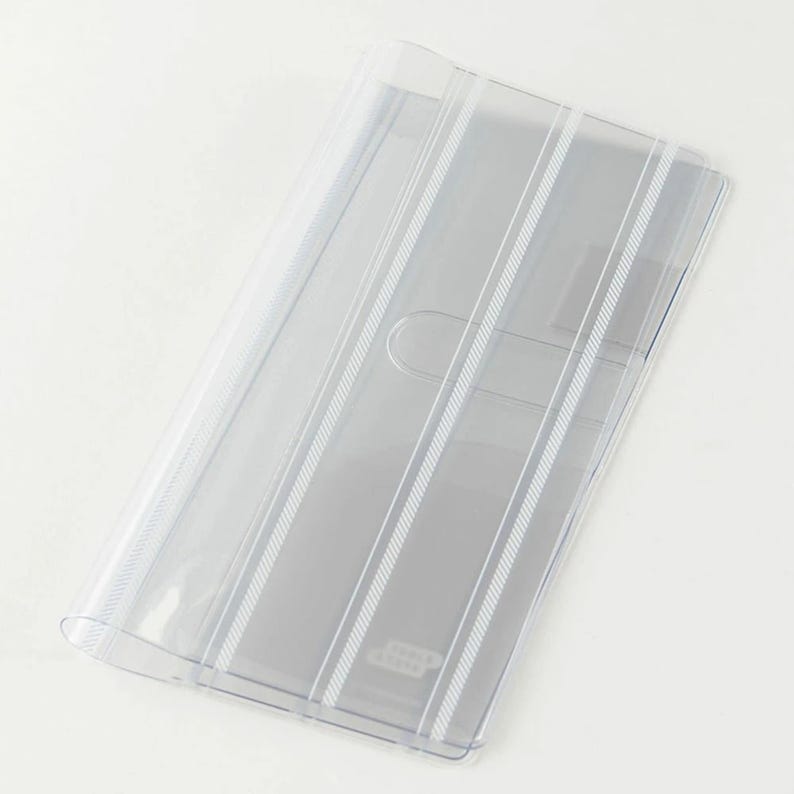 Puede incluir: Un portadocumentos de pl&aacute;stico transparente con detalles de rayas blancas verticales. El soporte tiene un borde curvo y un peque&ntilde;o recorte ovalado. El dise&ntilde;o es simple y funcional, ideal para organizar documentos.