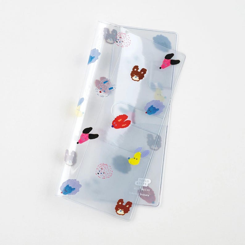 Puede incluir: Organizador de pl&aacute;stico transparente con dise&ntilde;os de animales bordados de colores, incluyendo osos, erizos y p&aacute;jaros. El organizador tiene m&uacute;ltiples bolsillos y un cierre a presi&oacute;n. El texto "TOY'S & TOYS NICHI Shoota" est&aacute; impreso en la parte inferior derecha.