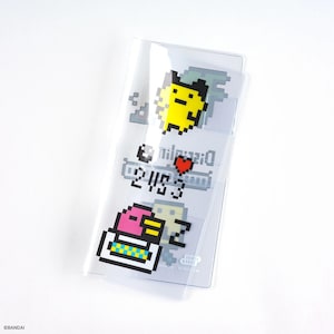 Puede incluir: Portatarjetas de pl&aacute;stico transparente con personajes de dibujos animados pixelados en amarillo, rosa y blanco. El soporte tiene texto y un coraz&oacute;n rojo. El dise&ntilde;o recuerda la est&eacute;tica de los videojuegos retro.