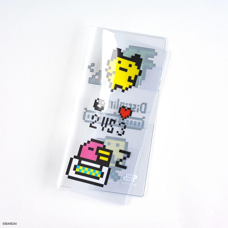 Puede incluir: Portatarjetas de pl&aacute;stico transparente con personajes de dibujos animados pixelados en amarillo, rosa y blanco. El soporte tiene texto y un coraz&oacute;n rojo. El dise&ntilde;o recuerda la est&eacute;tica de los videojuegos retro.