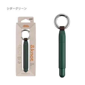 May include: A dark green &knot wearable carabiner pen with a silver metal ring, attached by a brown fabric strap. The pen features black 0.5 ink and is presented in a light brown cardboard retail box with the text &knot and uni branding.