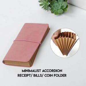 Puede incluir: Un archivador minimalista rosa en acordeón para recibos, facturas y monedas. La carpeta se cierra con una banda elástica. El interior es una serie de bolsillos marrones en forma de acordeón. El texto de la imagen dice: "MINIMALIST ACCORDION RECEIPT/ BILLS/ COIN FOLDER."