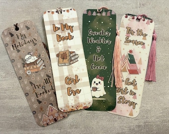 May include: Four decorative bookmarks with tassel accents. The bookmarks feature seasonal themes and text, including "My Holidays Are All Booked," "In My Book Girl Era," "Sweater Weather & Hot Cocoa," and "Tis the Season Get Lost in Story."
