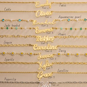 May include: A collection of gold-colored necklaces with various chain styles, including cable, twist, and paperclip. Each necklace features a name pendant in different fonts. Some necklaces have decorative elements like daisies, hearts, and aquamarine pearls.